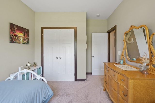 bedroom with a closet, light carpet, and baseboards