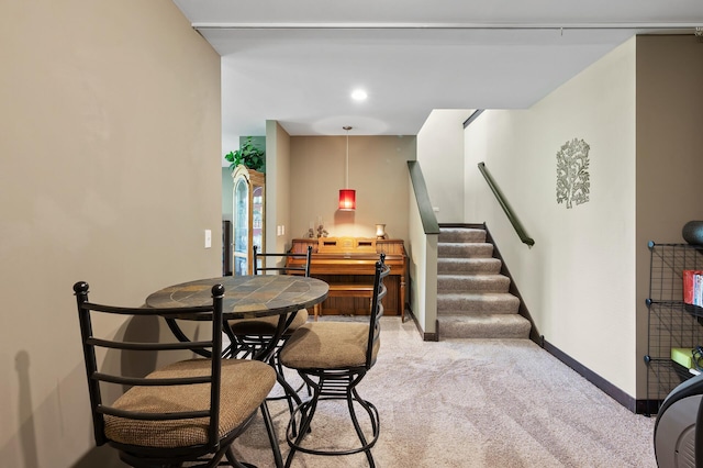 dining area featuring light carpet, stairway, and baseboards