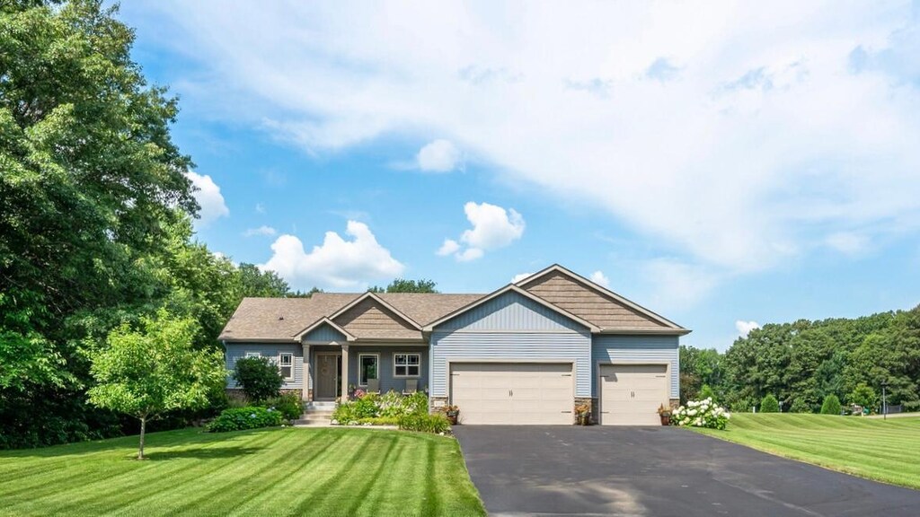 craftsman-style house with stone siding, driveway, a garage, and a front lawn