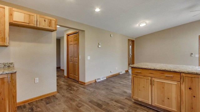 kitchen featuring light brown cabinetry, dark hardwood / wood-style flooring, and light stone countertops