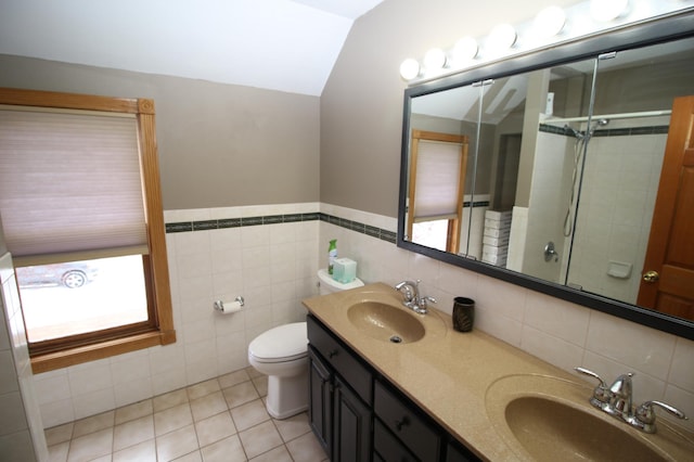 bathroom featuring a healthy amount of sunlight, vaulted ceiling, vanity, and tile walls