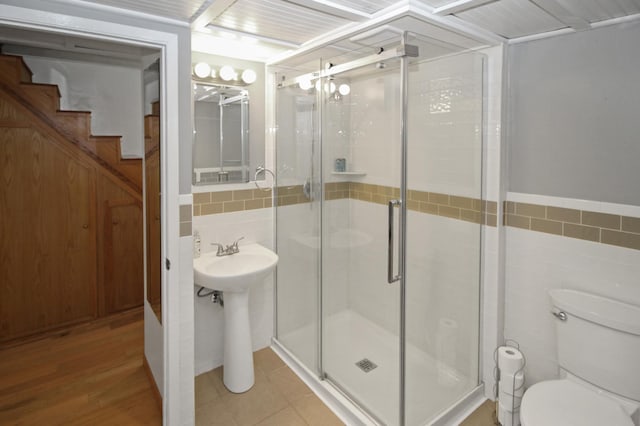 bathroom featuring toilet, an enclosed shower, sink, and tile walls