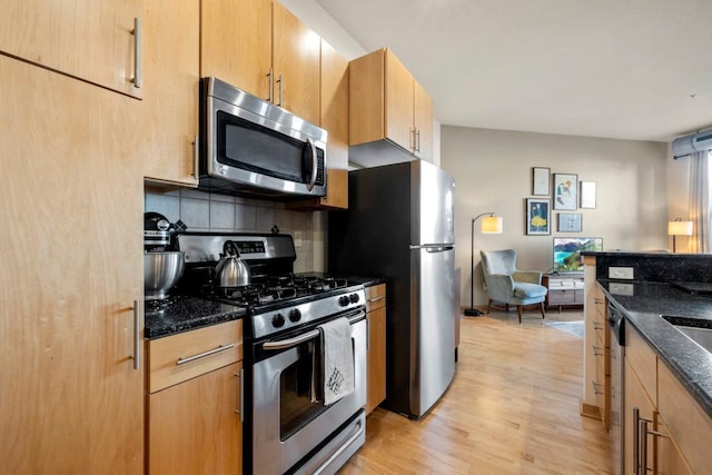 kitchen with decorative backsplash, stainless steel appliances, light wood-style floors, and dark stone counters