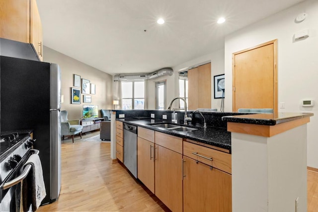 kitchen with dark stone countertops, light wood-style flooring, recessed lighting, stainless steel appliances, and a sink