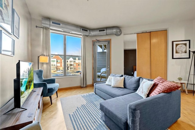 living room with light wood-style flooring, baseboards, and visible vents