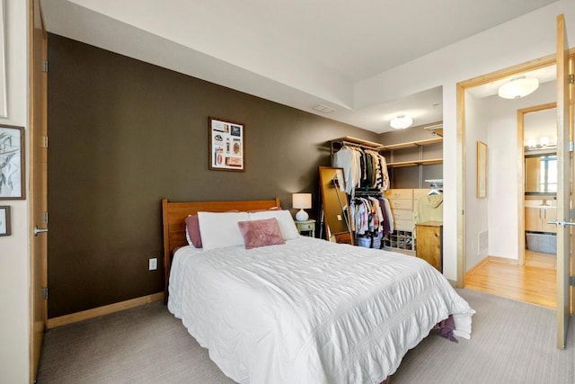 bedroom with a walk in closet, baseboards, and ensuite bathroom