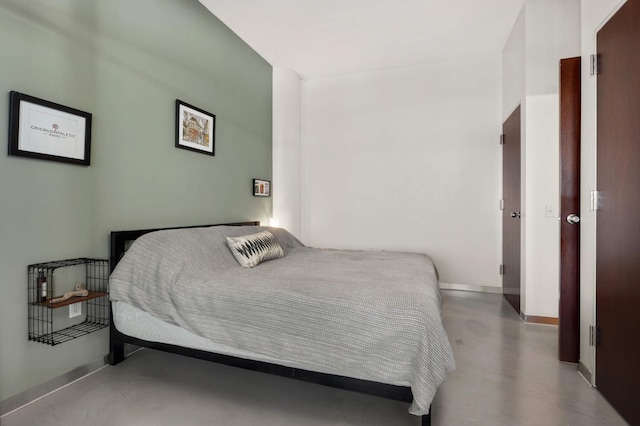 bedroom with concrete floors and baseboards