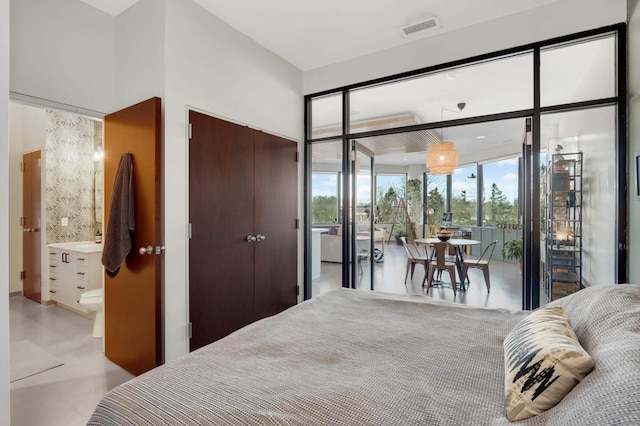 bedroom with ensuite bath, visible vents, a wall of windows, and a closet