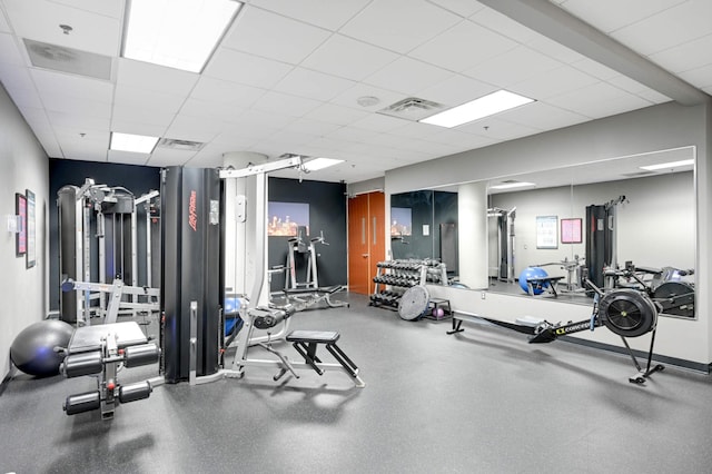 exercise room featuring a drop ceiling, visible vents, and baseboards