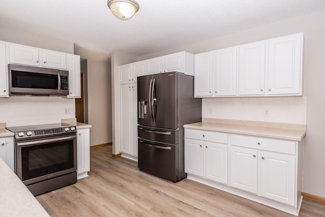 kitchen featuring white cabinetry, stainless steel appliances, light hardwood / wood-style floors, and decorative backsplash