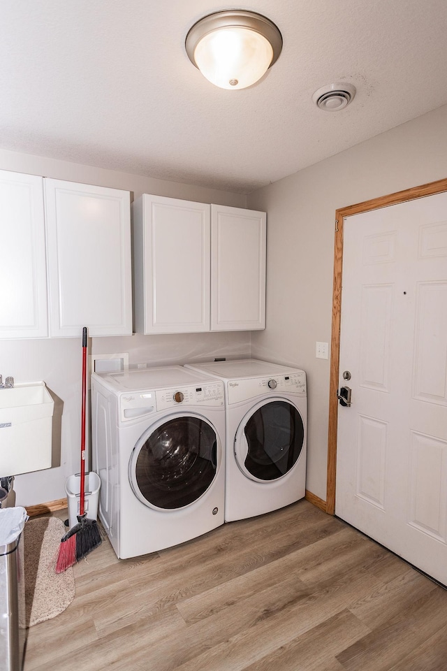 clothes washing area with cabinets, independent washer and dryer, sink, and light hardwood / wood-style flooring