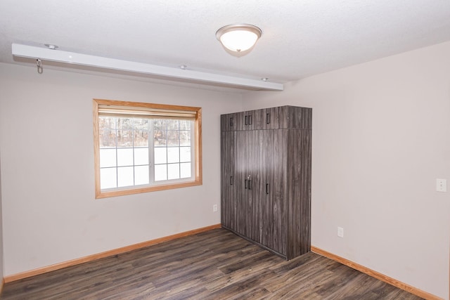 unfurnished bedroom with dark hardwood / wood-style floors, beam ceiling, and a textured ceiling