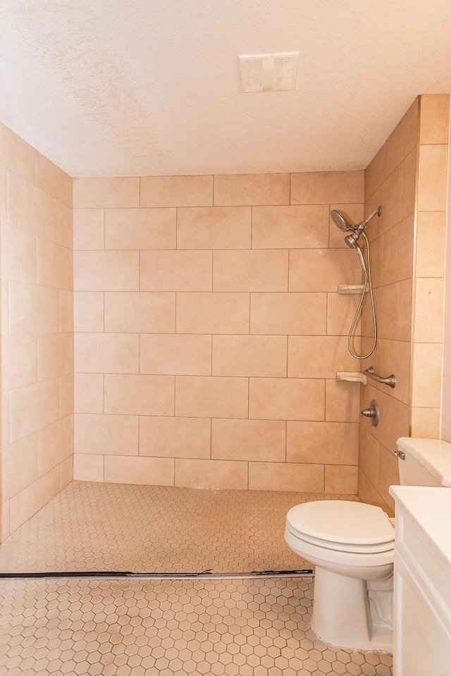 bathroom with tiled shower, vanity, and toilet