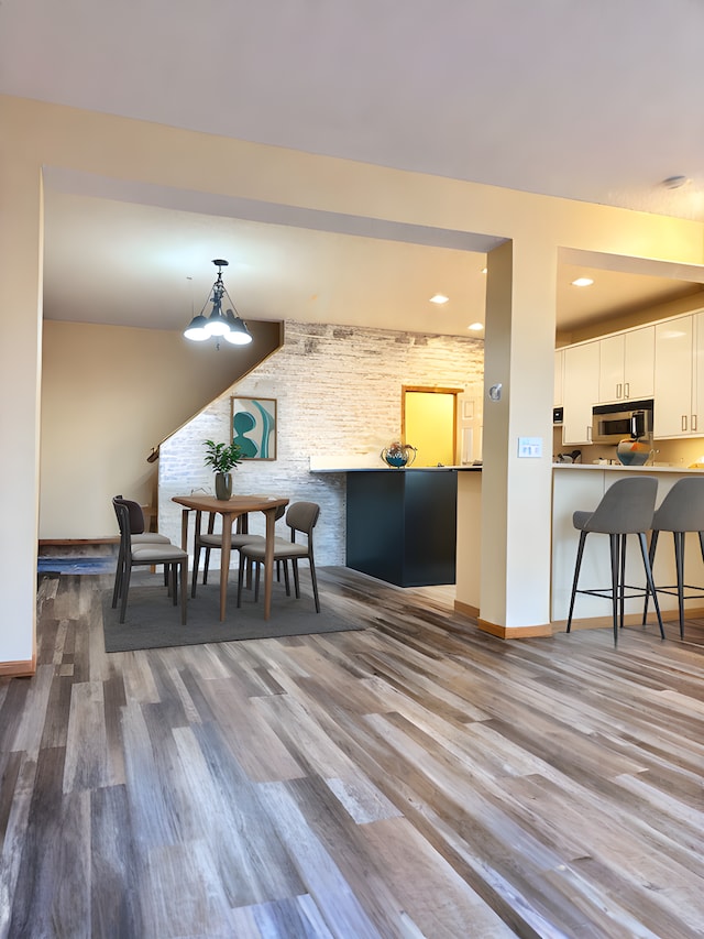 dining area with brick wall and light wood-type flooring