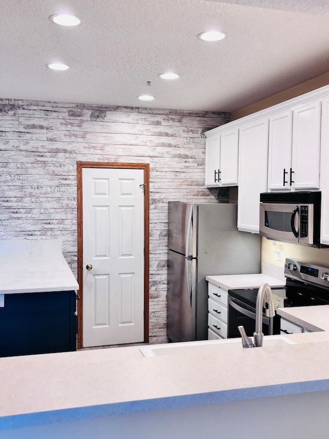 kitchen with white cabinetry, stainless steel appliances, and a textured ceiling