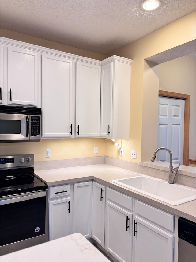 kitchen with stainless steel appliances, sink, white cabinets, and a textured ceiling