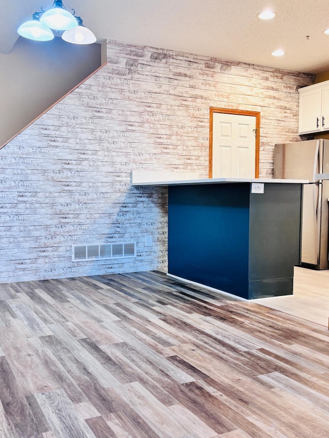 details with hardwood / wood-style flooring and stainless steel refrigerator