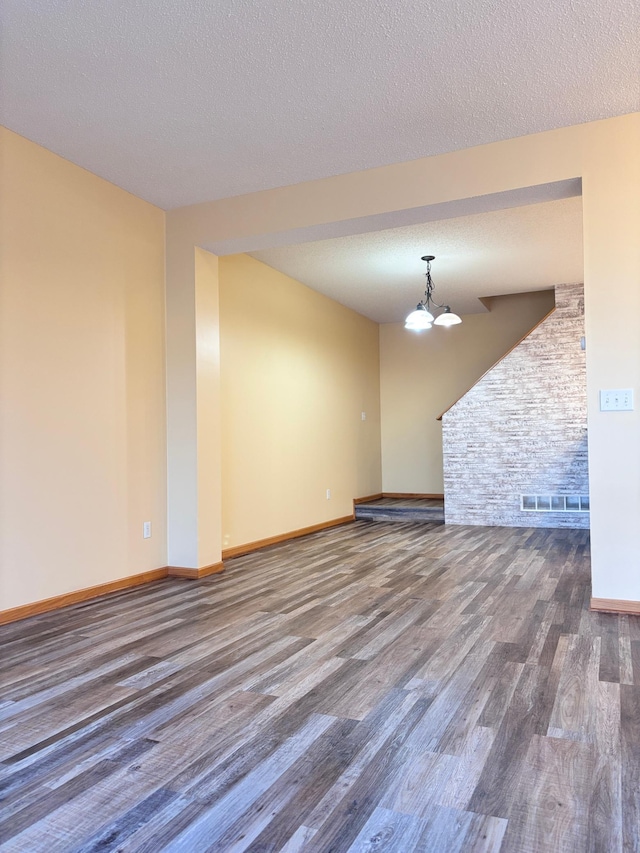 unfurnished room with an inviting chandelier, wood-type flooring, and a textured ceiling