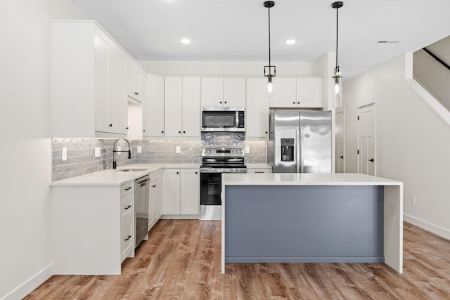 kitchen featuring stainless steel appliances, sink, a kitchen island, and white cabinets