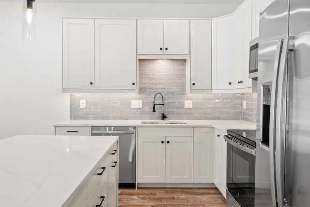 425 8th St Unit 23, New Richmond, WI 54017 - kitchen with appliances with stainless steel finishes, a sink, light wood-style floors, white cabinetry, and tasteful backsplash