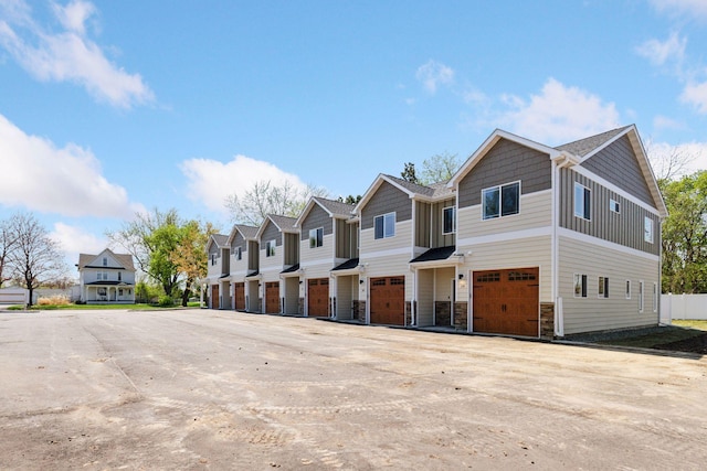 425 8th St Unit 23, New Richmond, WI 54017 - view of property featuring a garage, a residential view, driveway, stone siding, and board and batten siding
