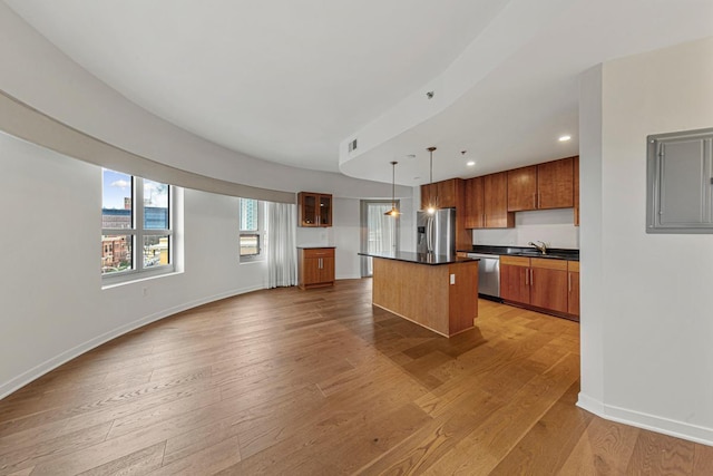 929 Portland Ave Unit 406, Minneapolis, MN 55404 - kitchen with stainless steel appliances, a sink, brown cabinets, dark countertops, and a kitchen island