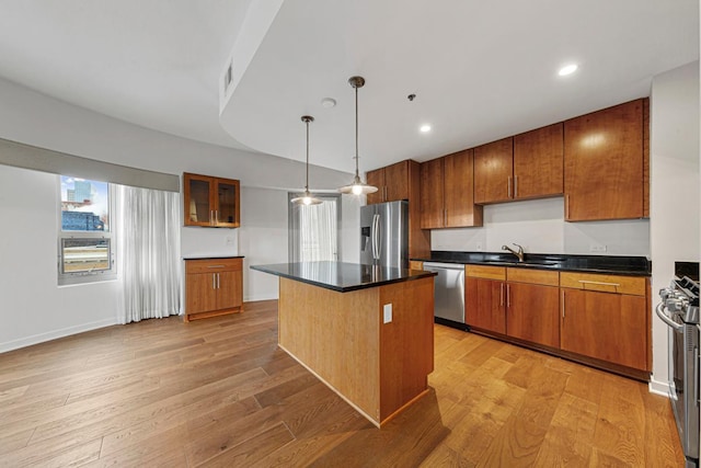 929 Portland Ave Unit 406, Minneapolis, MN 55404 - kitchen featuring appliances with stainless steel finishes, a sink, brown cabinetry, light wood-style flooring, and a center island