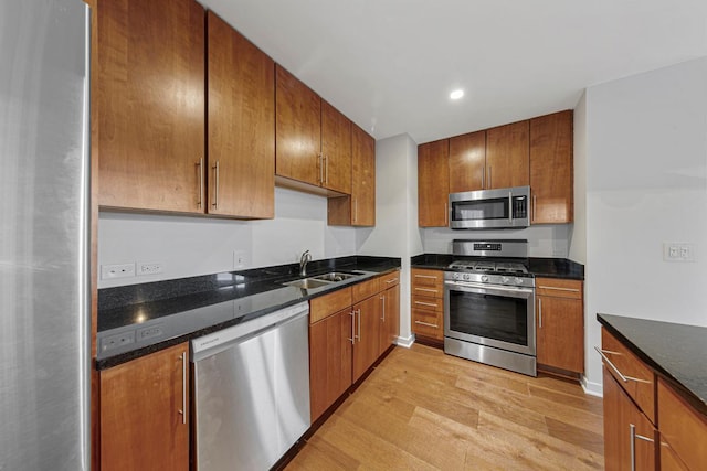 929 Portland Ave Unit 406, Minneapolis, MN 55404 - kitchen with appliances with stainless steel finishes, a sink, light wood-style floors, brown cabinets, and dark stone countertops
