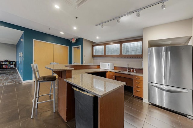 929 Portland Ave Unit 406, Minneapolis, MN 55404 - kitchen featuring freestanding refrigerator, a sink, white microwave, light stone counters, and dark tile patterned flooring