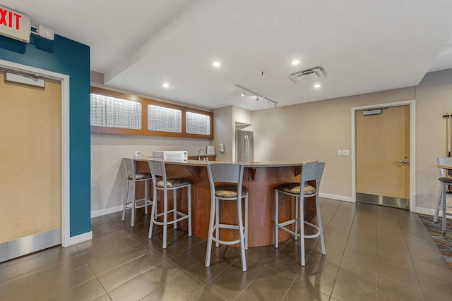 929 Portland Ave Unit 406, Minneapolis, MN 55404 - kitchen with freestanding refrigerator, white microwave, baseboards, a kitchen breakfast bar, and dark tile patterned floors