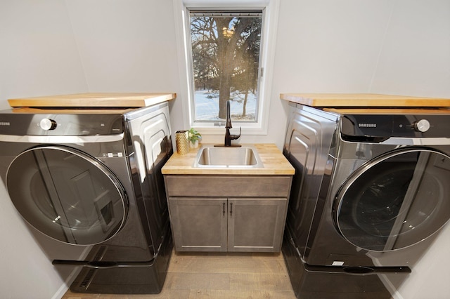 laundry area featuring sink, washing machine and dryer, and light hardwood / wood-style floors