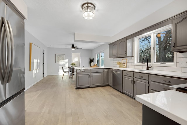 kitchen featuring stainless steel appliances, sink, gray cabinetry, and backsplash