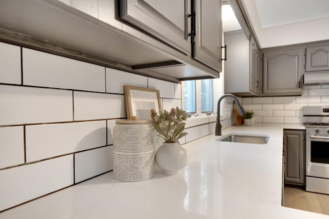 kitchen with electric stove, backsplash, sink, and gray cabinetry