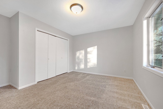 unfurnished bedroom with light carpet and a closet