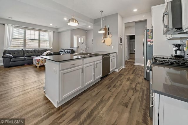 kitchen with stainless steel appliances, white cabinetry, sink, and pendant lighting