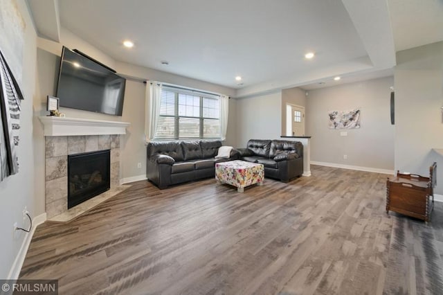 living room with a tiled fireplace and hardwood / wood-style floors