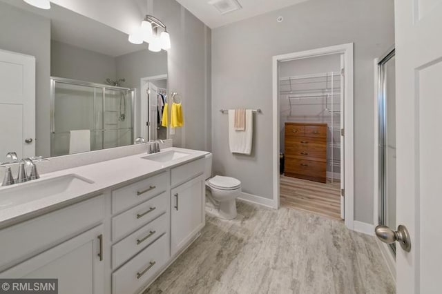 bathroom featuring vanity, hardwood / wood-style floors, a shower with door, and toilet