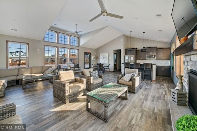 living room with hardwood / wood-style flooring, a fireplace, high vaulted ceiling, and ceiling fan