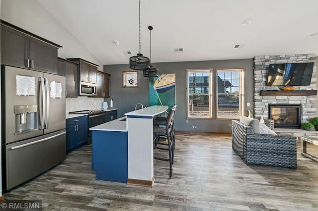 kitchen with tasteful backsplash, a kitchen bar, dark brown cabinetry, stainless steel appliances, and a center island with sink