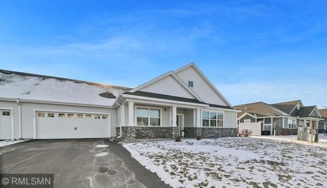 view of front of house with driveway, stone siding, and an attached garage