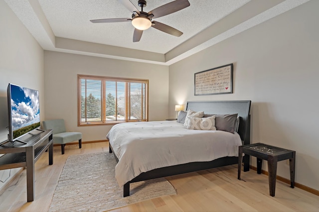 bedroom with a raised ceiling, baseboards, and wood finished floors