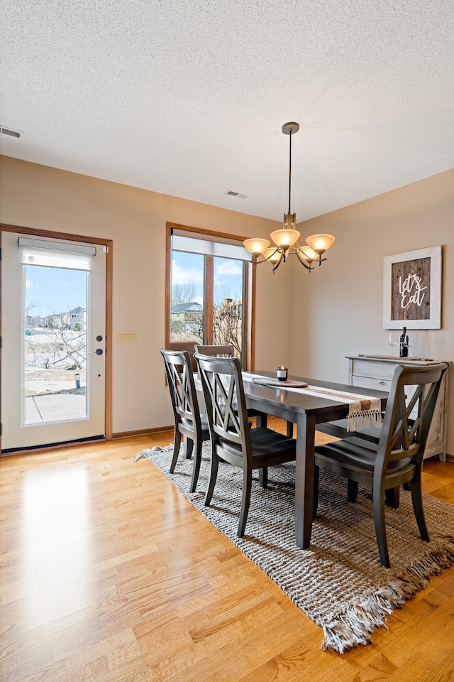 dining space featuring light wood finished floors, visible vents, and a healthy amount of sunlight