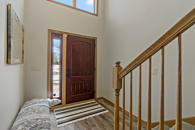 entrance foyer featuring a towering ceiling, baseboards, stairway, and wood finished floors