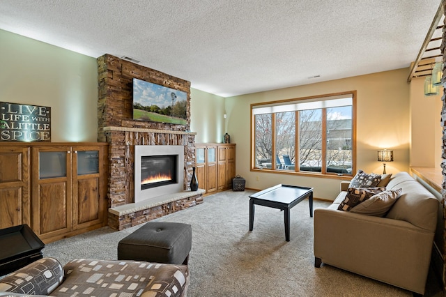 living room with a textured ceiling, a glass covered fireplace, visible vents, and light colored carpet