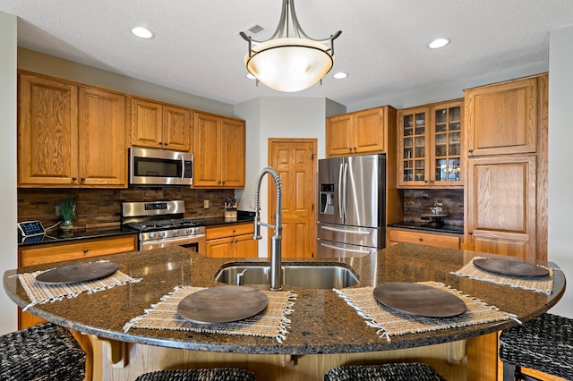 kitchen featuring pendant lighting, brown cabinets, stainless steel appliances, a spacious island, and a sink