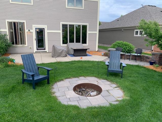 back of property with an outdoor fire pit, a lawn, and a patio