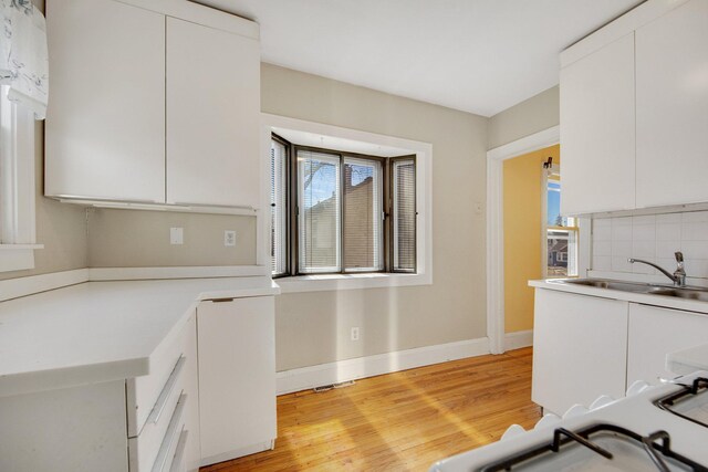 5421 30th Ave S, Minneapolis, MN 55417 - kitchen featuring white cabinetry, sink, decorative backsplash, and light wood-type flooring
