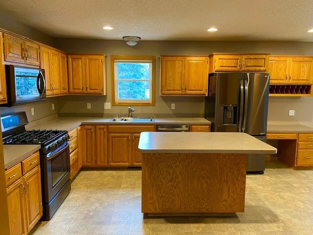 kitchen featuring a kitchen island, built in desk, sink, stainless steel appliances, and a textured ceiling