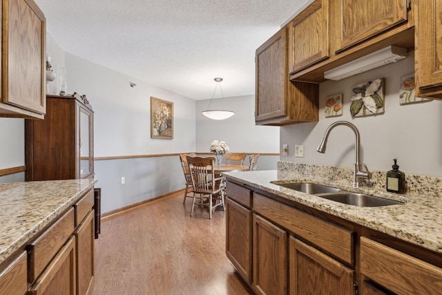 kitchen with decorative light fixtures, light hardwood / wood-style floors, sink, and a textured ceiling