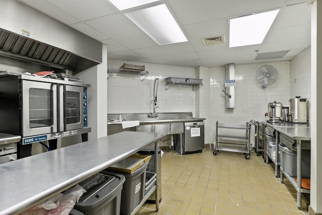 kitchen featuring dishwasher, stainless steel counters, tile walls, wine cooler, and a drop ceiling